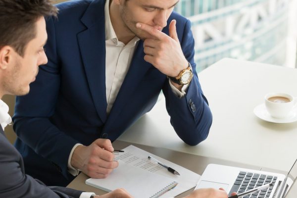 Entrepreneurs discussing work results on meeting Business partners using laptop while working together on important corporate project in office. Businessman attentively listening to adviser Investment specialist making presentation of promising deal