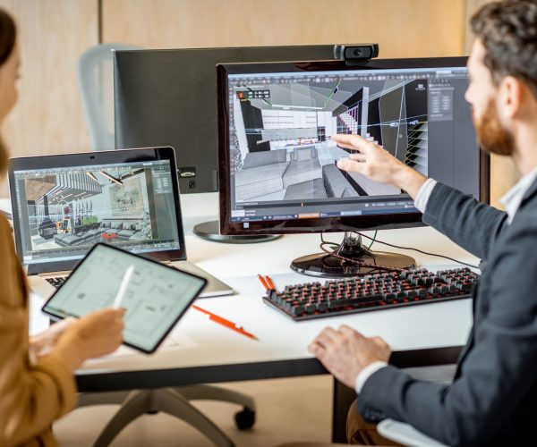 Two interior designers working in the office Two creative office employees making interior design on the computer and digital tablet at the modern office of architectural firm. Concept of 3d modeling and digital Interior designing